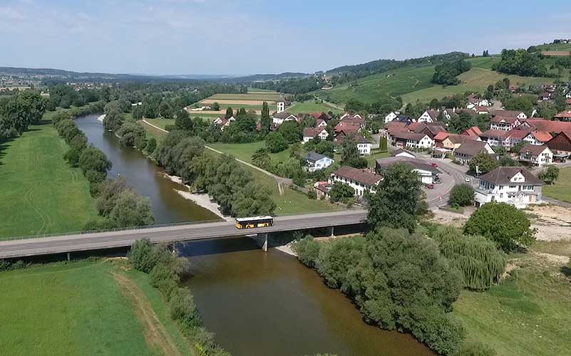 Flusslandschaft mit Brücke und Dorf